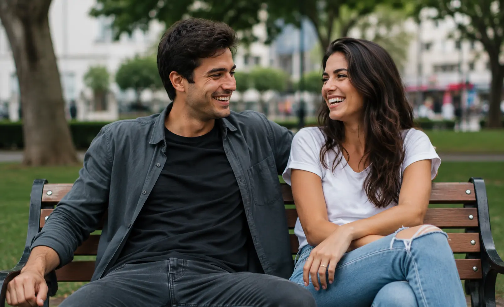 Two close friends laughing together on a park bench with a relaxed and casual atmosphere.